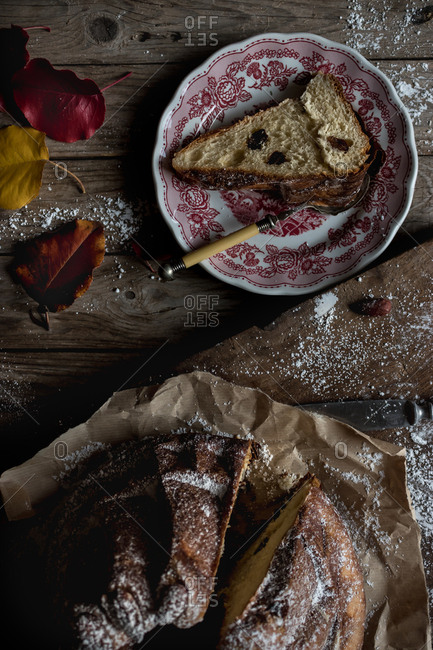 Delicate autumn leaves lying on shabby timber tabletop near plate and parchment paper with yummy fresh Kugelhopf