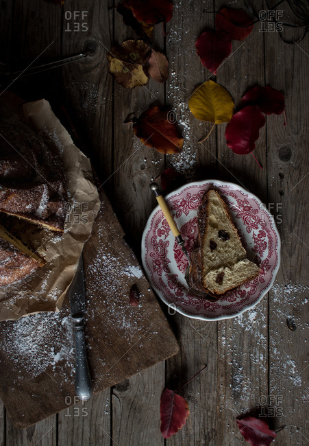 Delicate autumn leaves lying on shabby timber tabletop near plate and parchment paper with yummy fresh Kugelhopf