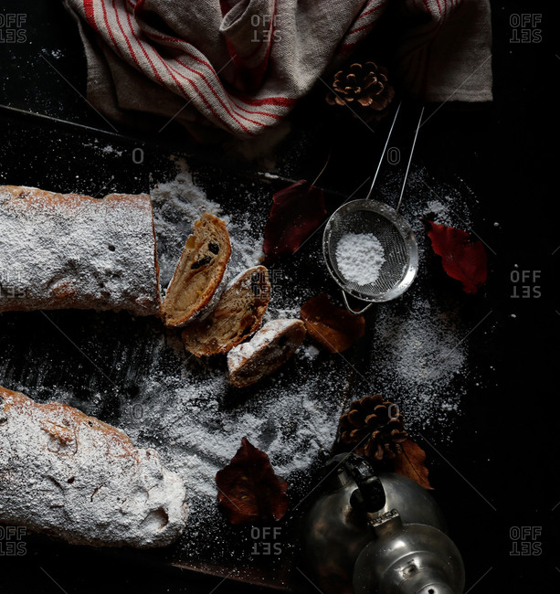 Pieces of delicious fresh Stollen covered with powdered sugar lying on dark tabletop