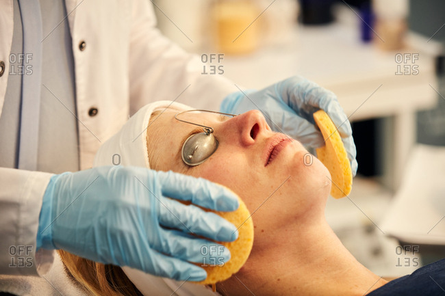 Dermatologist giving client a facial with sponges