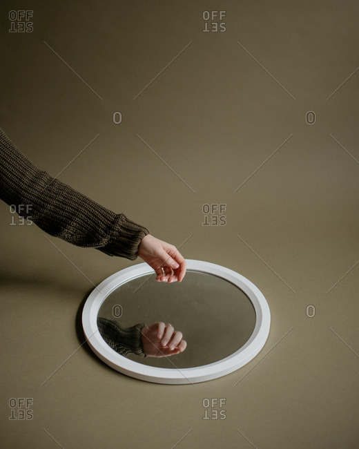 Hand hovering round mirror in green studio.