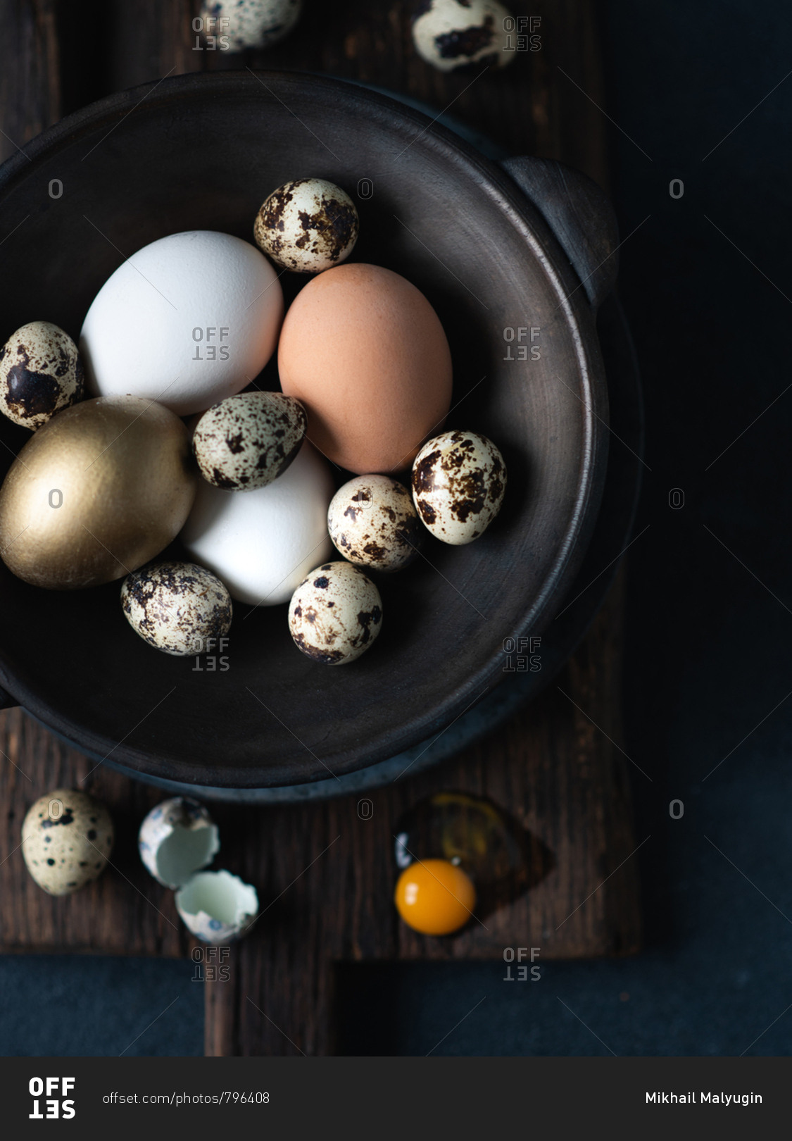 Easter eggs in dark ceramic bowl over dark background, view from above