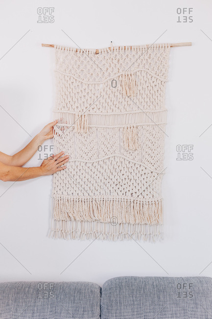 Female hands arranging a wall hanging macrame.