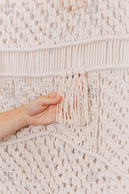 Female hands arranging a wall hanging macrame threads.