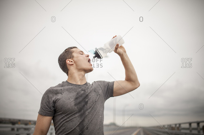 Male athlete pouring water trying to rehydrate during workout outdoors, Montreal, Quebec, Canada