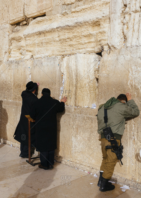 January 13, 2019: Orthodox men and soldier with gun praying at the wailing wall known also as the western wall in the old city, Jerusalem, Israel.