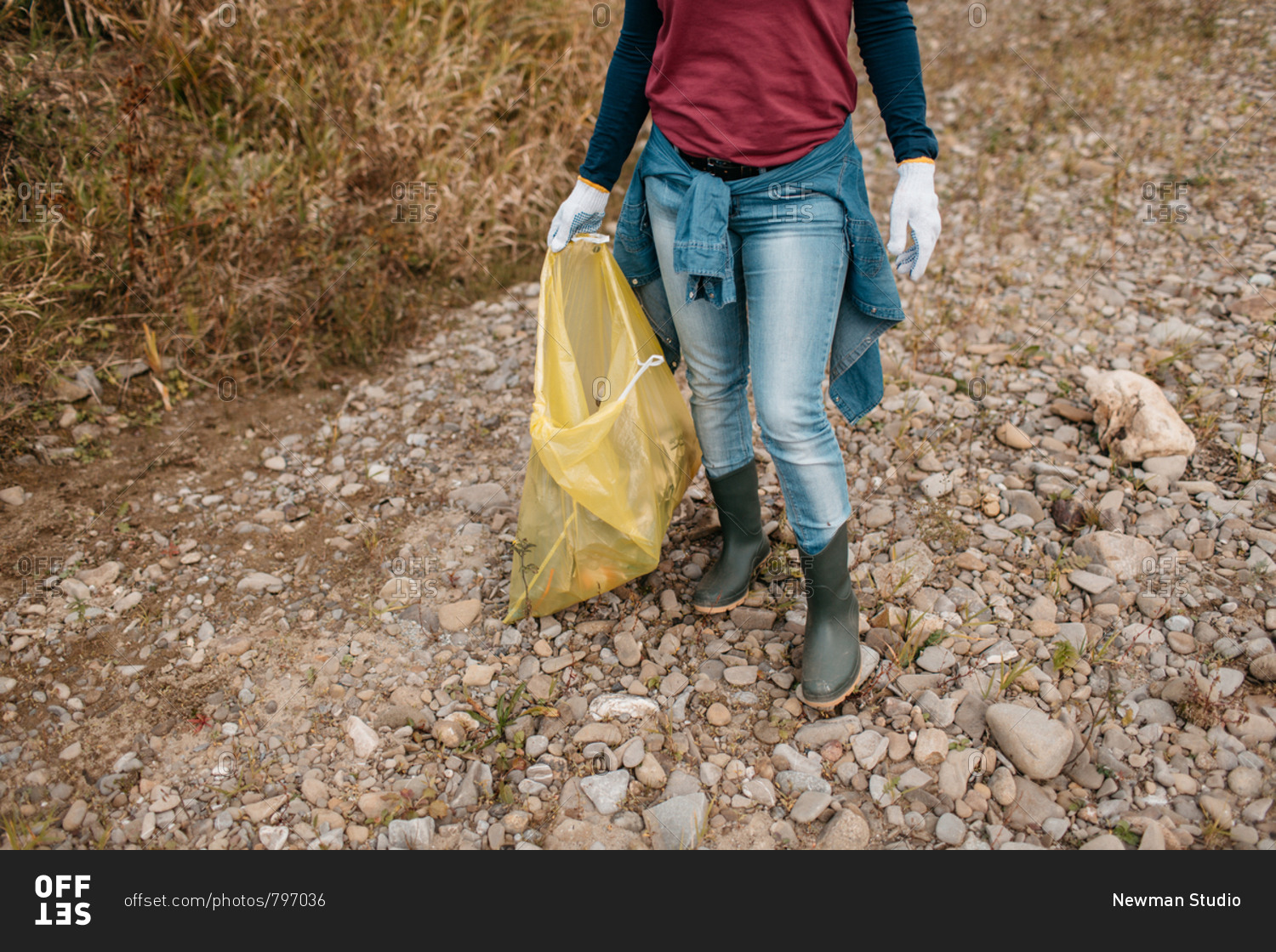 Cropped image of female volunteer carrying yellow plastic bag filled with rubbish