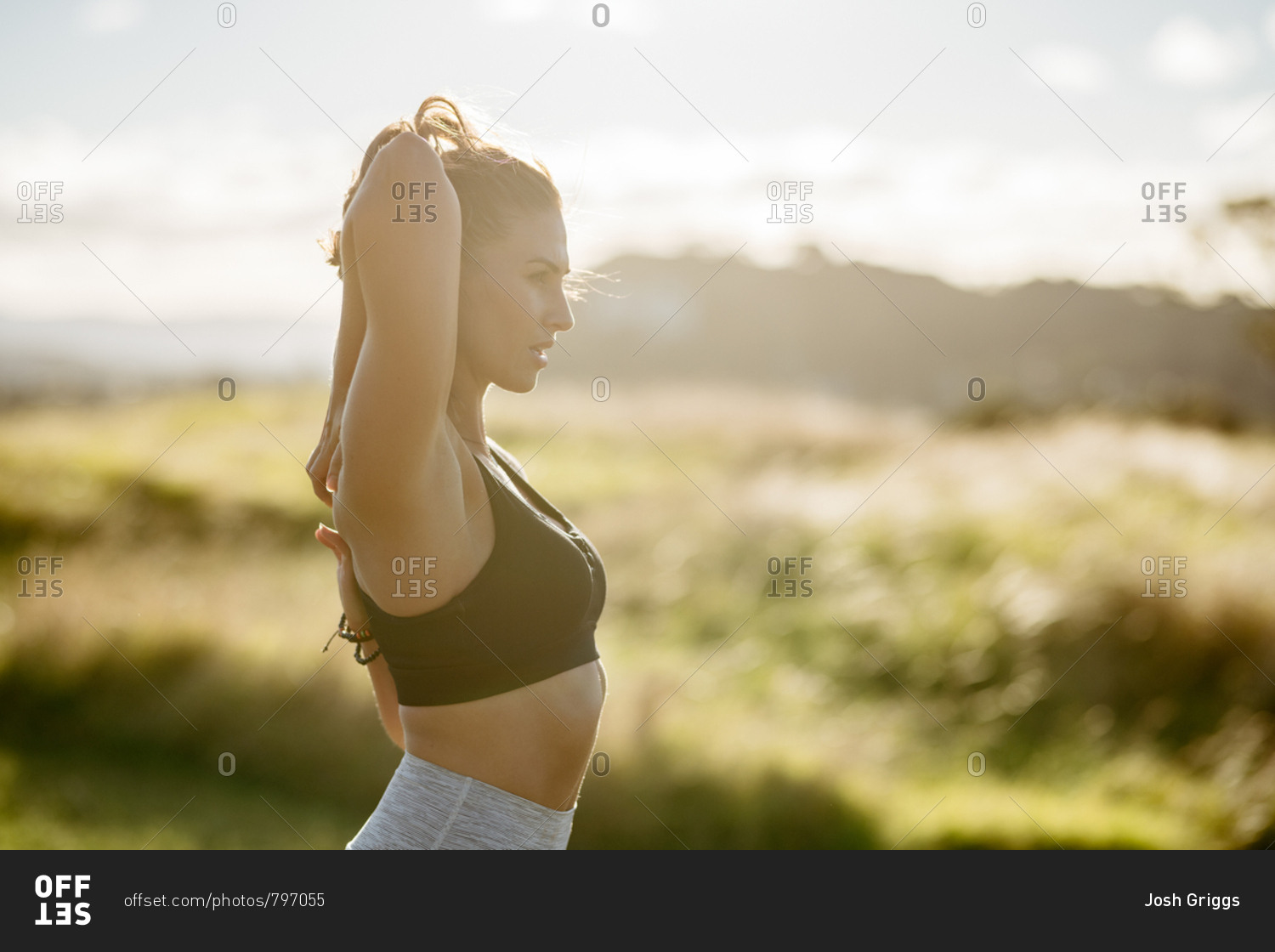 Beautiful woman stretching her arms before workout in the countryside