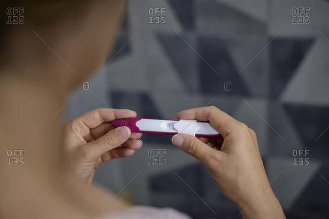 Close-up of woman checking her pregnancy test showing positive