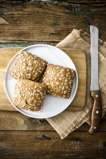 Three whole meal bread rolls with oat flakes on plate