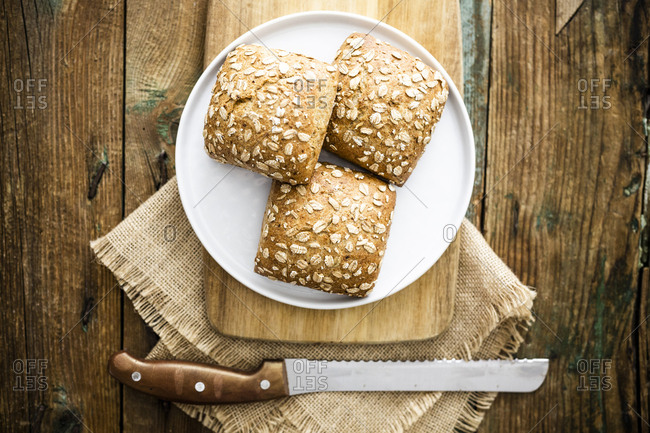 Three whole meal bread rolls with oat flakes on plate