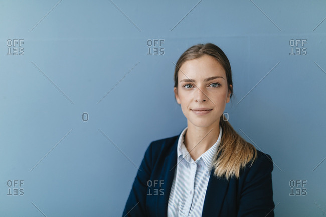 Portrait of a young businesswoman against blue background