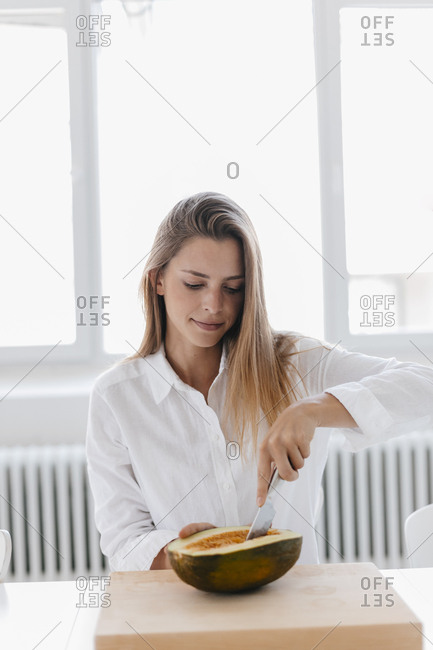 Young woman pitting half of a melon