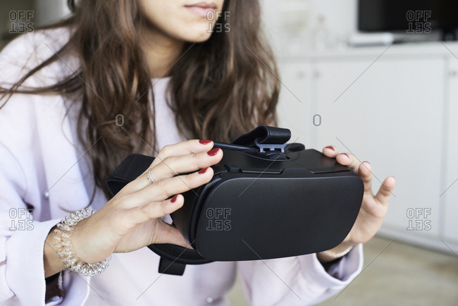 Faceless female holding virtual reality headsets at home