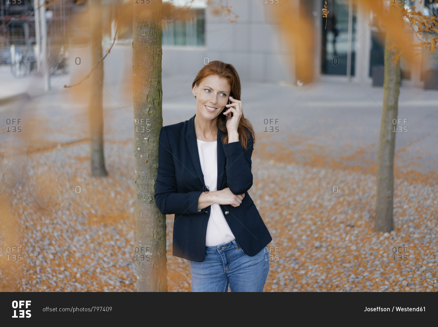 Smiling businesswoman on cell phone outdoors in the city in autumn