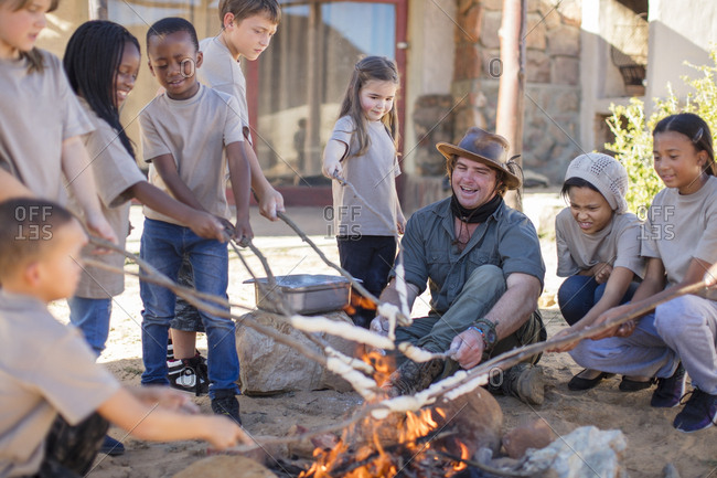 Children and guide roasting twist bread at camp fire
