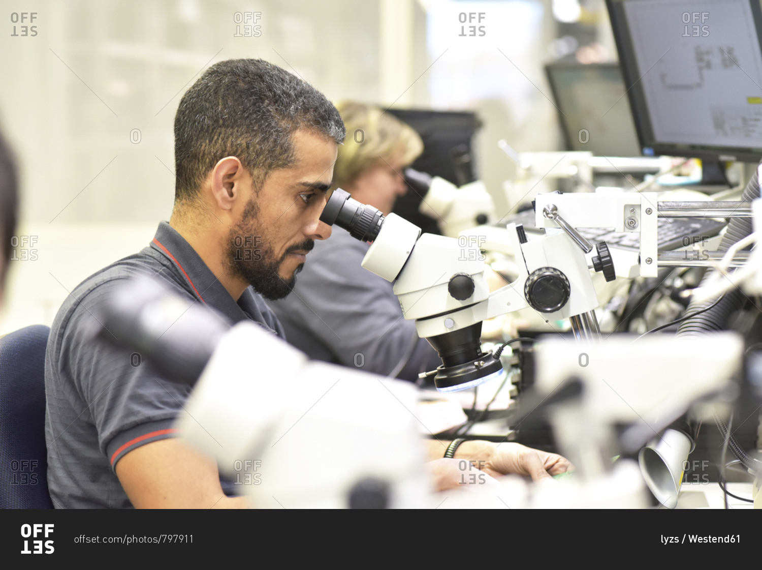 Man using a microscope for the quality control in the manufacturing of circuit boards for the electronics industry