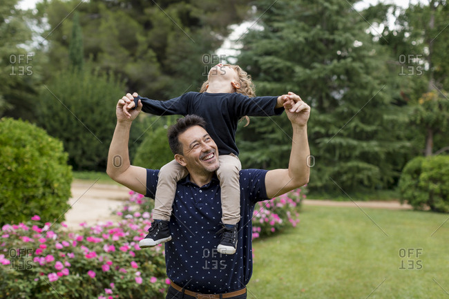 Happy father carrying son on shoulders in park