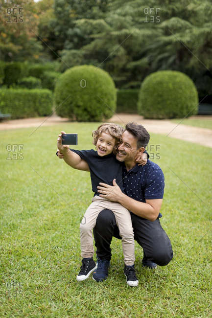 Happy father and son on taking a selfie in park