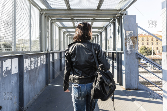 Rear view of young woman walking on a bridge