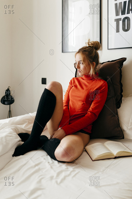 Young blonde woman sitting on a pillow stock photo - OFFSET