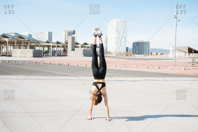 Young woman head stand with city on the background
