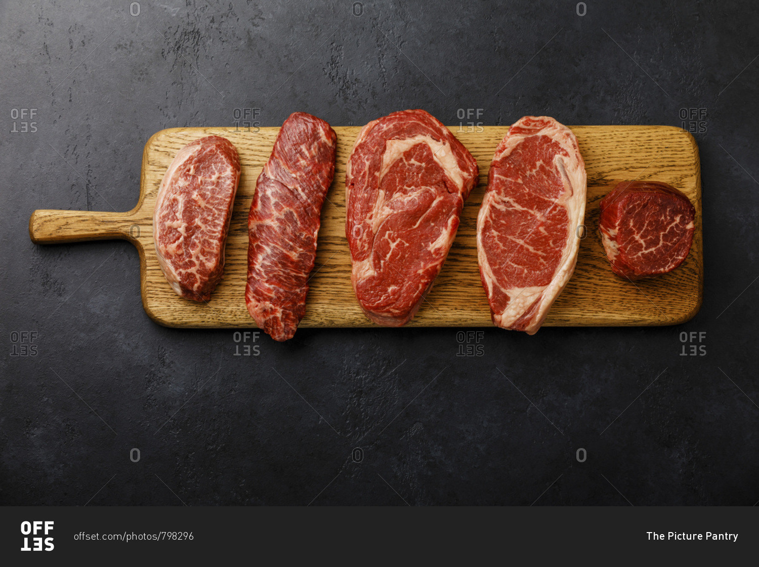 Variety of Raw Black Angus Prime meat steaks Top Blade, Denver, Rib Eye, Striploin, Tenderloin fillet Mignon on wooden board on dark background
