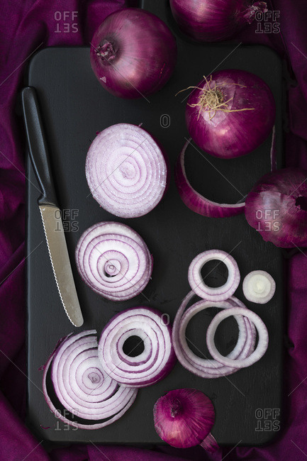 Sliced and whole red onions on a cutting board.