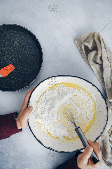 Woman mixing gluten free crepe batter in a large ceramic bowl.