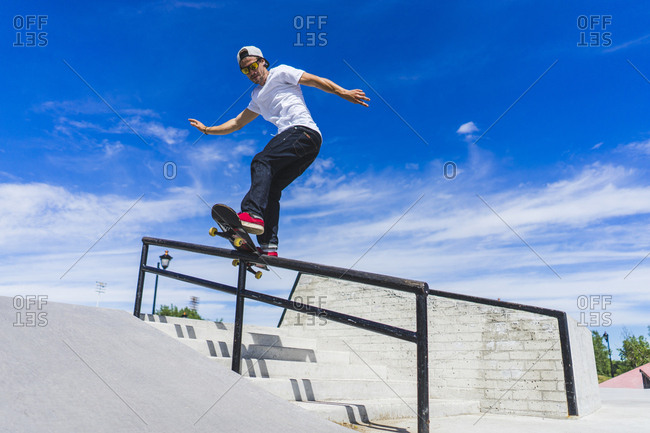 Male athlete on skateboard sliding down handrail, Montreal, Quebec, Canada