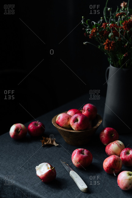Apples and knife on table beside flowers