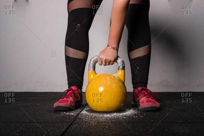 athletic young concentrated woman in sportswear upping kettle bell in gym