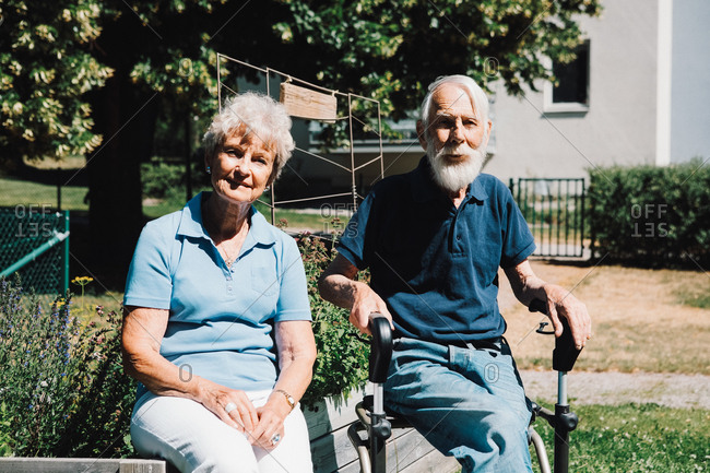 Portrait of smiling retired senior man and woman sitting at back yard