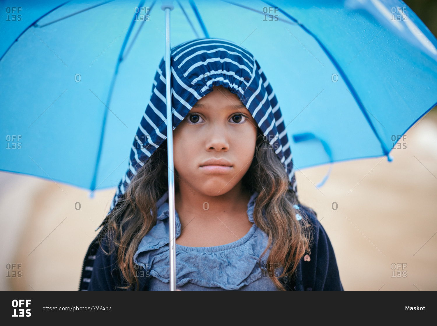 Portrait of girl with umbrella wearing raincoat during rainy season