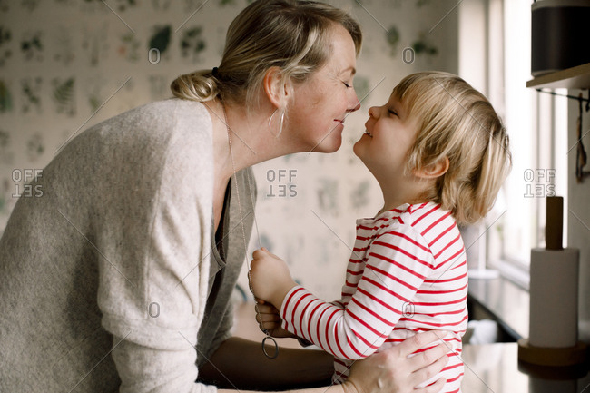 Side view of playful mother and daughter spending leisure time in kitchen at home