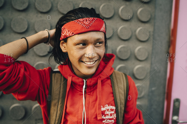 Cheerful young man wearing red bandana while looking away in city