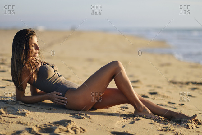 Beautiful young woman wearing bikini lying on beach stock photo - OFFSET