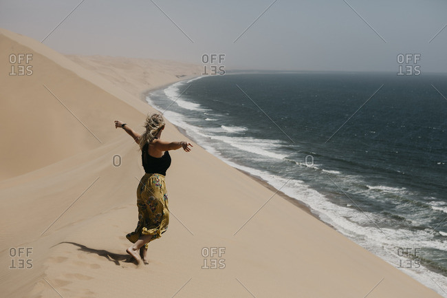 Namibia- Walvis Bay- Namib-Naukluft National Park- Sandwich Harbour- woman walking in dune landscape at the sea