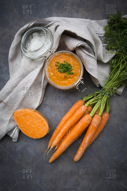 Glass of sweet potato carrot soup garnished with chives