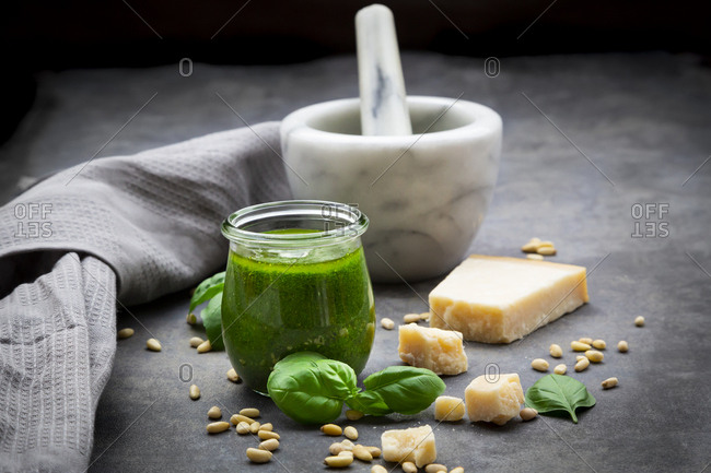 Glass of homemade pesto Genovese- ingredients- mortar and kitchen towel