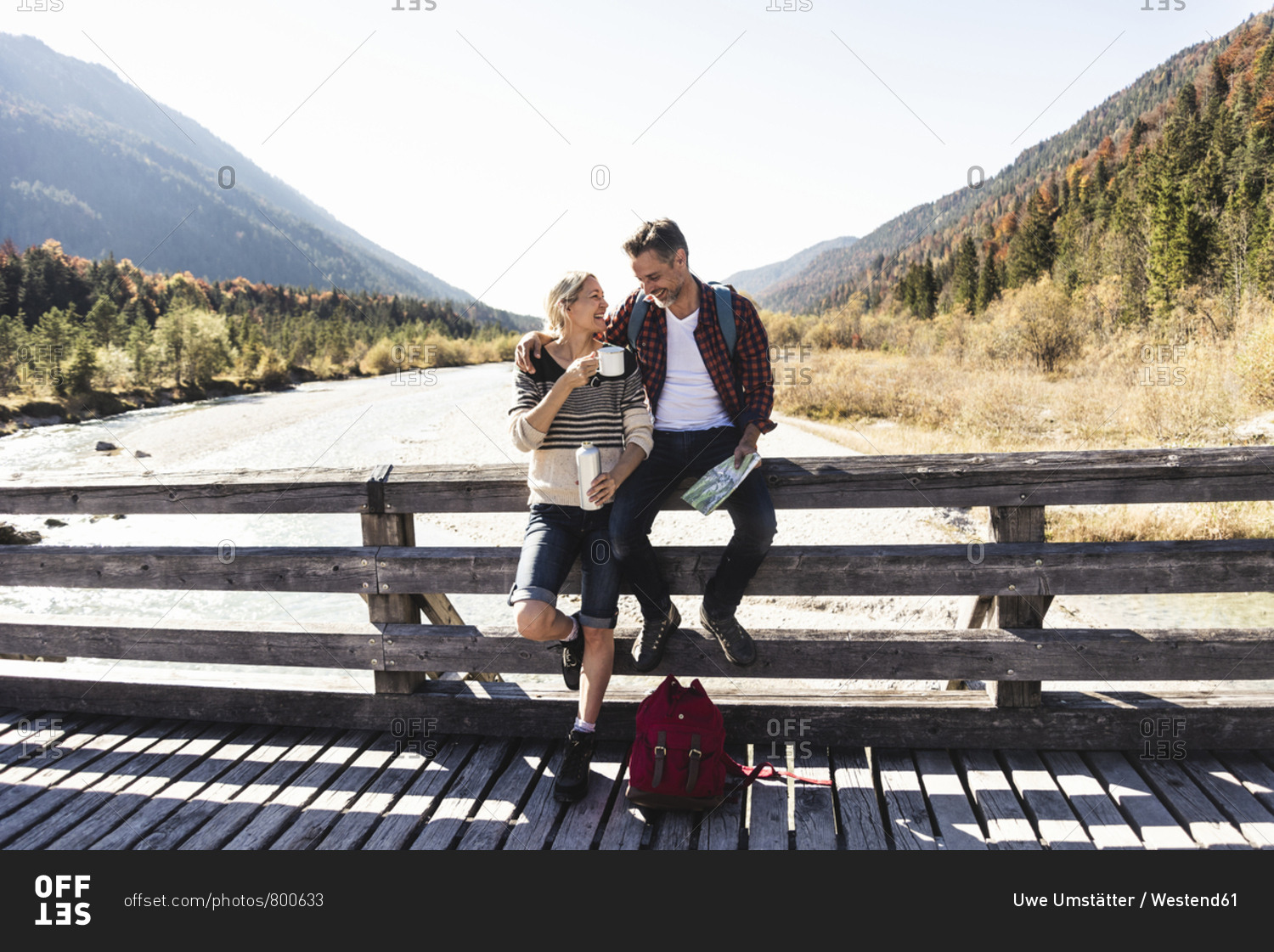 Austria- Alps- couple on a hiking trip having a break on a bridge