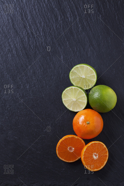 Limes and tangerines on black slate slab