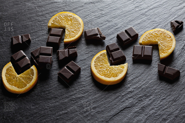 Cocolate pieces with orange slices on black slate