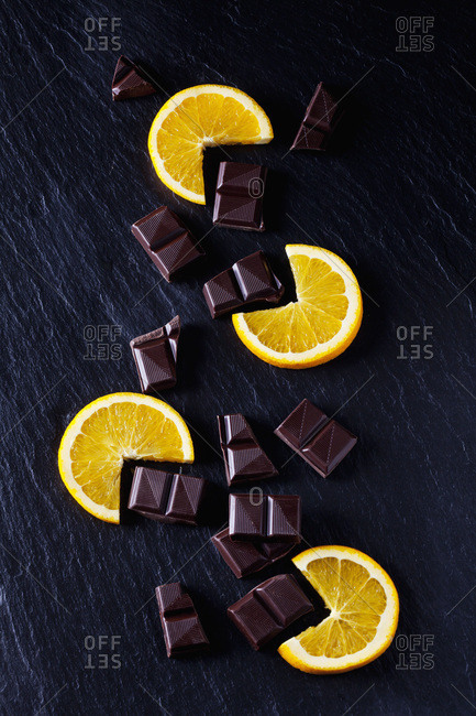 Cocolate pieces with orange slices on black slate