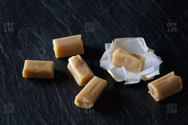 Cream toffees and wrapping paper on black slate