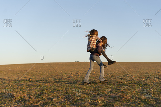 Girl giving her sister a piggyback ride outdoors