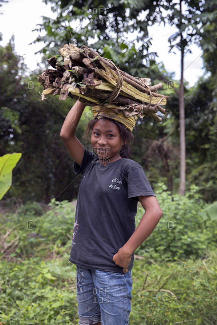 July 19, 2013: INDONESIA, Flores, portrait of a young girl carrying wood on her head in Dintor village