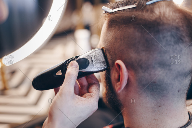 Male Hairstylist Shaving Clients Hair Using An Electric