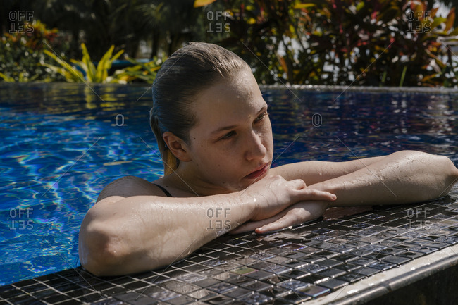 Portrait of a beautiful young woman in a water pool resting in the hotel pool.
