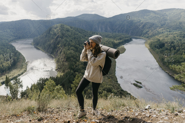 Beautiful young woman with backpack and film camera takes pictures.